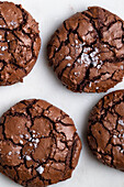 Top view of sweet freshly baked chocolate brownie cookies with cracks placed on white background in light kitchen at home