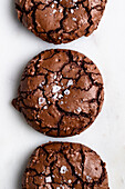 Top view of sweet freshly baked chocolate brownie cookies with cracks placed on white background in light kitchen at home