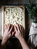 Top view of faceless person preparing raw dough for bread placed on baking paper on table