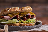 Nahaufnahme eines leckeren Sandwiches mit Pastrami, Salat, Schinken und Gurken