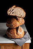 Tasty sourdough bread with brown crust placed on marble table against black backdrop