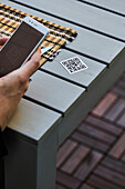 Ernte von oben, nicht erkennbarer Mann, der ein Smartphone benutzt und den QR-Code der Speisekarte eines Restaurants scannt