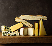 Verschiedene geschnittene Käse auf einem Holzbrett auf einem Holztisch