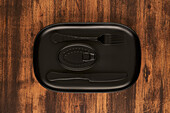 Draufsicht auf eine schwarze Gabel und ein Messer, die neben versiegelten Konserven auf einem rechteckigen schwarzen Tablett liegen