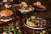 Appetizing vegetarian dishes with sauteed mushrooms and vegetables near burger and ice cream with French toast on wooden table