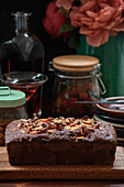Leckerer gebackener Pfundskuchen mit Mandelblättchen, serviert auf einem Holzbrett auf einem Tisch mit alkoholischem Getränk und Beeren
