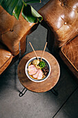 Top view of delicious traditional ramen soup in bowl with chopsticks served on round table