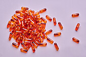 Top view Komposition von orangefarbenen Pillen auf rosa Hintergrund in hellen Studio verstreut