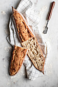 Blick von oben auf einen leckeren hausgemachten Laib Brot, der auf einem Tuch auf einem Marmortisch liegt
