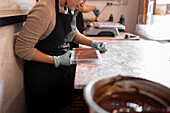Soft focus of bowl with liquid chocolate and spoon placed on table near digital scale and confectioner