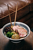 From above delicious traditional ramen soup in bowl with chopsticks served on round table