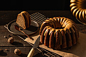 From above coffee walnut bundt cake placed on baking net on dark rustic wooden table in kitchen