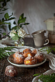 Hausgemachte Puddingcremekrapfen mit Zucker bestreut auf rustikalem Holztisch mit Tischtuch und Blätterdekoration