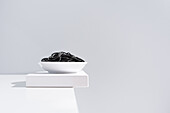 Minimalist studio with black squid ink spaghetti in full ceramic bowl on white table