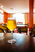 Glas Bier auf einem Holztisch in einer Kneipe vor unscharfem Hintergrund