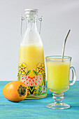 Front view of cocona juice in a glass and glass bottle on the table