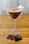 Glas süßer alkoholischer Cocktail aus Espressolikör, Milch und Schokolade auf einem Holztisch