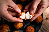 From above of crop anonymous chef demonstrating filling of cheese ball in crispy crust in kitchen