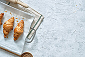 Draufsicht auf leckere frische Croissants auf einem Metalltablett auf dem Tisch in der Küche