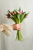 Crop unrecognizable female in romantic dress standing with bunch of tender colorful flowers
