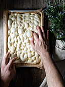 Top view of faceless person preparing raw dough for bread placed on baking paper on table