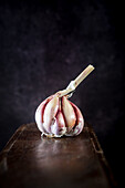 Ganzer frischer Knoblauch auf einem schäbigen Holztisch in einer rustikalen Küche mit dunklem Hintergrund