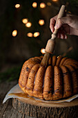 Delicious homemade chocolate cake on wooden trunk tray against black background with fairy lights