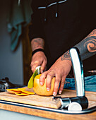 Anonyme Frau schneidet frischen, reifen Kürbis auf einem hölzernen Schneidebrett, während sie das Mittagessen in einem Wohnwagen während einer Reise in Kantabrien vorbereitet