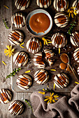 Top view pile of tasty freshly baked cookies with caramel and chocolate drizzle served on wooden table in light kitchen