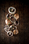 Top view of fresh raw champignons and sprigs of herbs placed on rustic wooden table