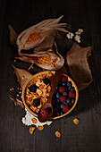 Von oben leckere Cornflakes mit frischen Waldbeeren in einer Schüssel neben Sackleinen beim Frühstück in einem dunklen Raum