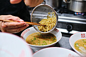 Stockfoto eines unbekannten Kochs in einem japanischen Restaurant, der Nudelsuppe serviert