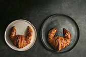 Top view composition with appetizing freshly baked crusty croissants served on white and black plates on table