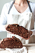 Crop faceless woman hands holding freshly baked sourdough rye bread Crumb pan cutting in half