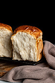 Köstliche geteilte Hälften von Sandwich-Brot auf Grill-Tablett auf Theke und Schneidebrett vor dunklem Hintergrund platziert