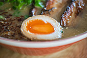 Stock photo of yummy ramen soup with boiled egg and meat in japanese restaurant.