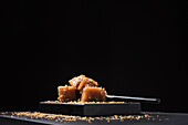 Gourmet quince jelly paste in ceramic plate sprinkled with sesame seeds on black background