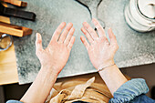 Crop unrecognizable female in apron showing palms of hands with flour after cooking in house