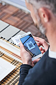 Ernte von oben, nicht erkennbarer Mann, der ein Smartphone benutzt und den QR-Code der Speisekarte eines Restaurants scannt