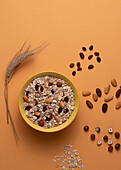 From above crispy granola with nuts in bowl on light table brown background