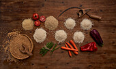 Top view of arranged small heaps of organic grains with fresh tomatoes and beans and other vegetables on wooden table near sickle and bunch of wheat