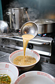 Stock photo of unrecognized chef in japanese restaurant serving noddles soup.