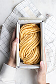 Top view of faceless female at table with raw dough prepared for Babka dessert and placed in metal baking dish