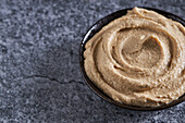 From above of fresh hummus served in bowl on cracked gray marble table in kitchen