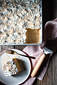 From above three milks cake in baking dish and plates with cups of strong coffee on wooden table