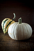 Whole fresh decorative pumpkins with striped peel on dark background