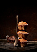 Tasty sweet baked muffins stacked on top of each other near spoon on black background