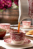 Aromatischer heißer Tee wird in eine Keramiktasse gegossen, die auf dem Frühstückstisch zu Hause steht