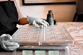 Soft focus of unrecognizable person in gloves weighing plastic molds on digital balance during chocolate preparation in confectionery