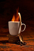 Ceramic mug of hot aromatic drink with fire and spoon place on surface near pile of fresh baked oatmeal cookies